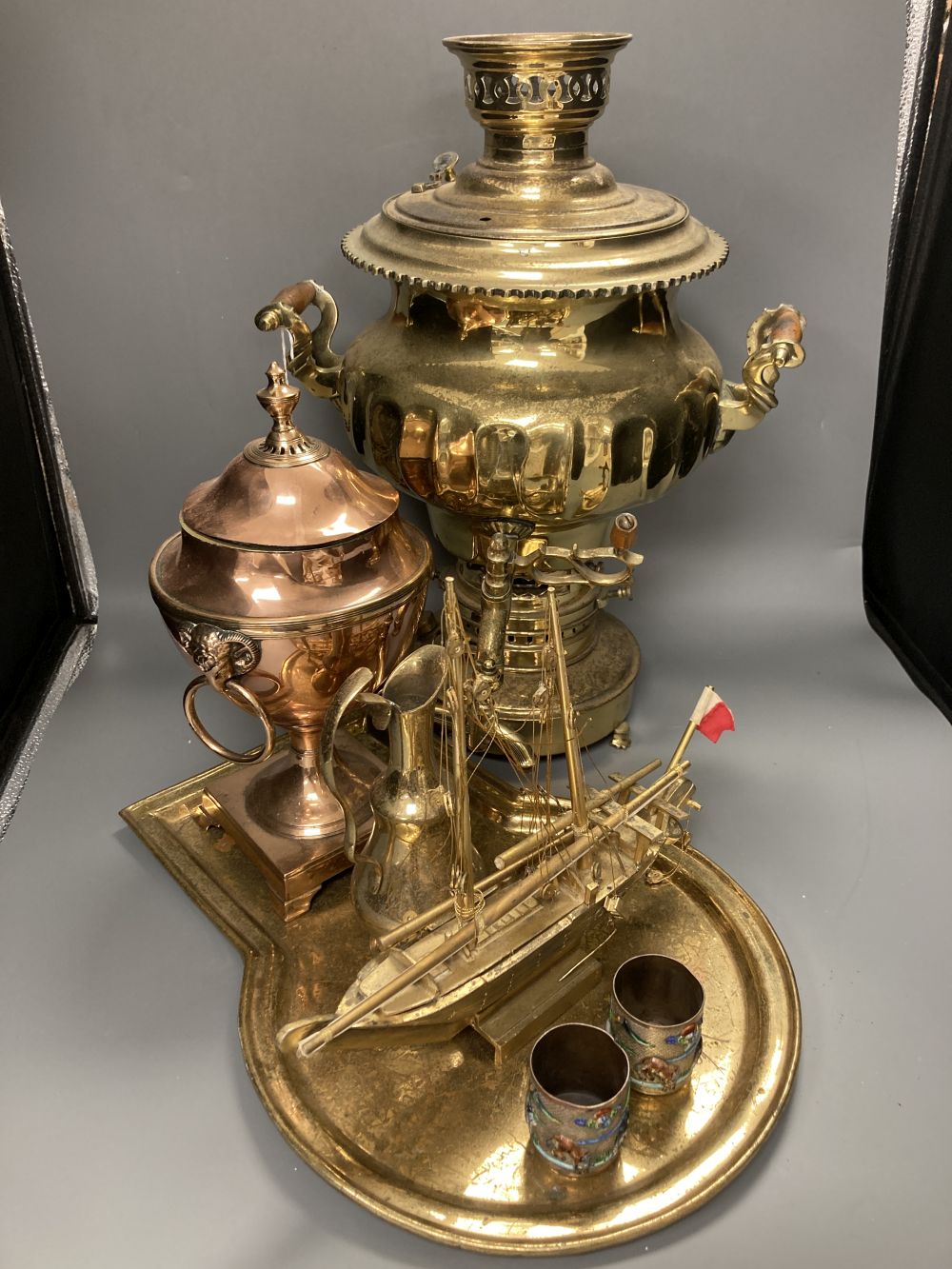A Russian brass samovar and stand, height 47cm, a copper tea urn, a brass jug and a pair of champleve mugs